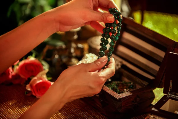 Female hands open box and touch bead decorations.