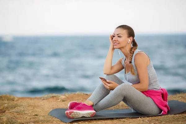 Sporty woman listening to music sitting on the beach