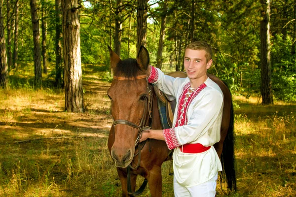 Young Ukrainian with a horse in the forest