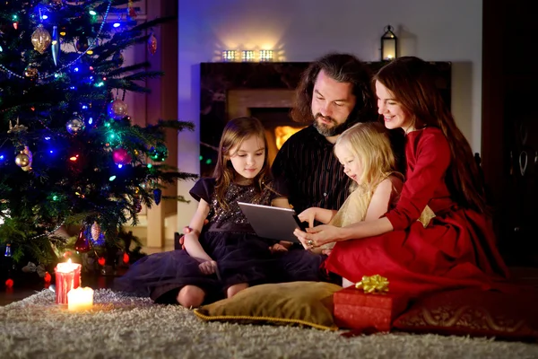 Family using a tablet pc at home by a fireplace