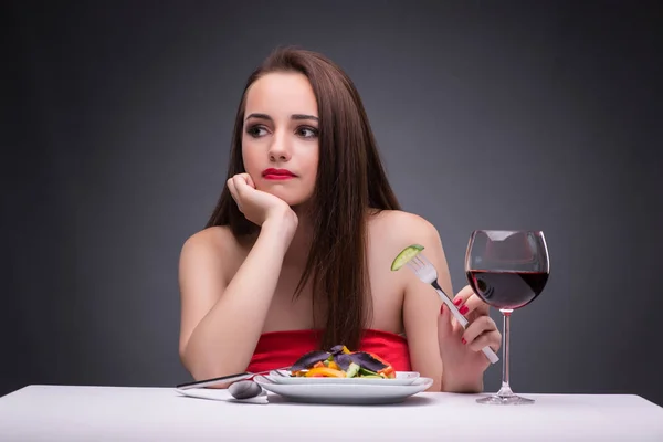 Beautiful woman eating alone with wine