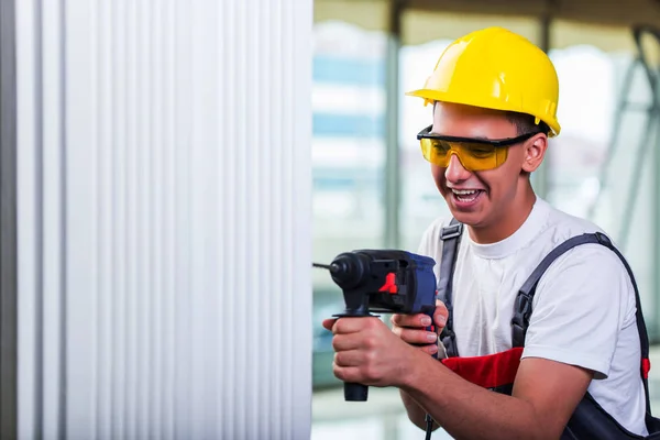 Man drilling the wall with drill perforator