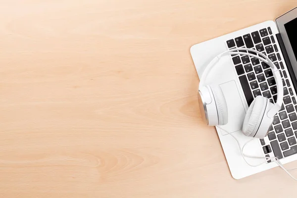 Headphones over laptop on wooden table