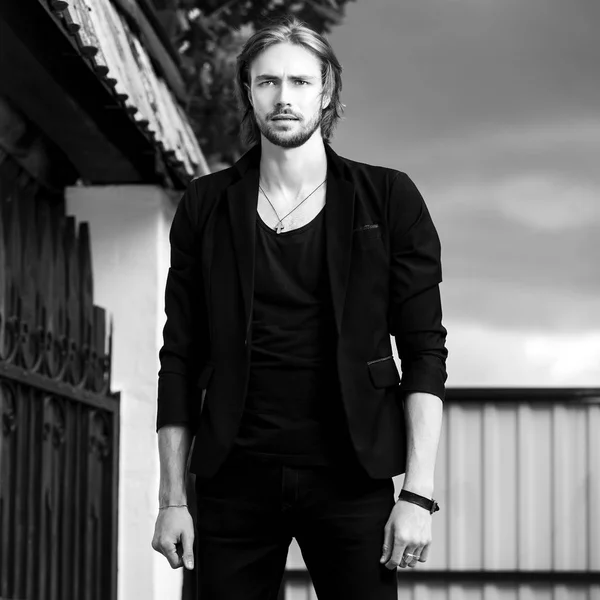 Black-white outdoor portrait of elegant long hair handsome man.