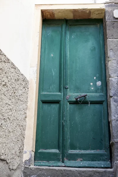 Green door with mailbox and bronze handles in the stone wall background.
