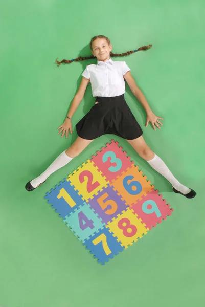 School girl is lies in front of a rug with numbers