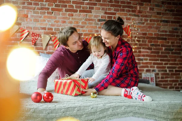 The daddy and mum give daughter the Christmas gift in bright packing