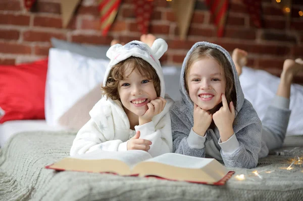 Two children, brother and sister, read Christmas tales.