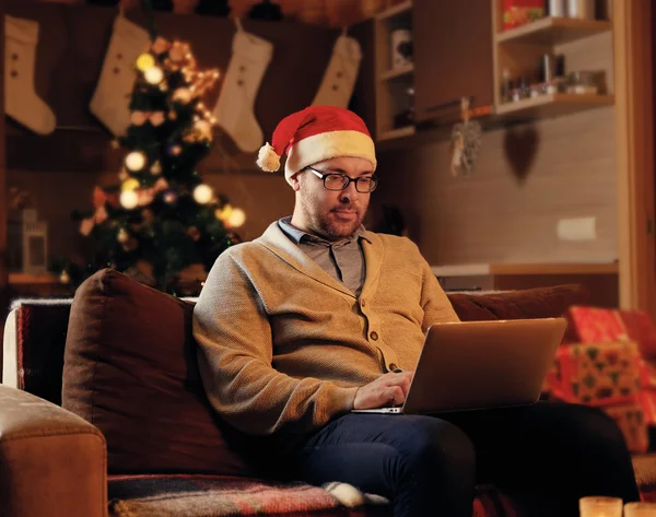 A man in Santa\'s hat working with laptop