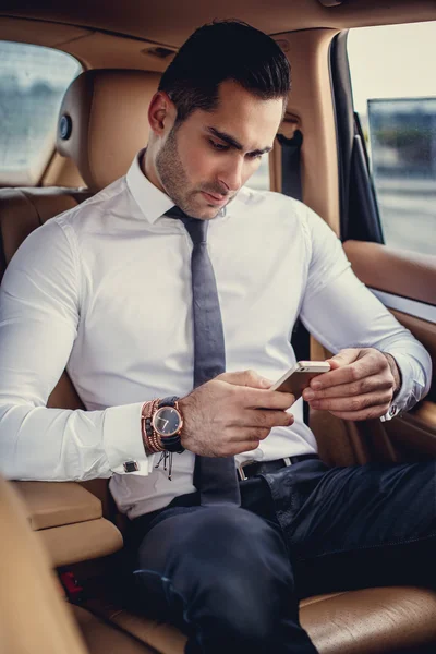 Man in a white shirt using smartphone.