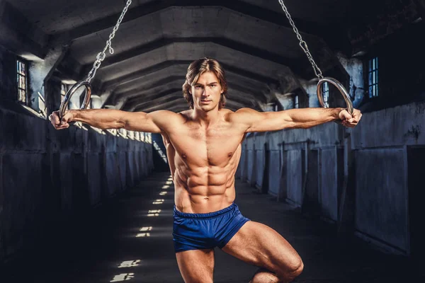 Muscular man posing with gymnastic rings
