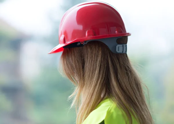Redhead female architect wearing a red protective helmet.