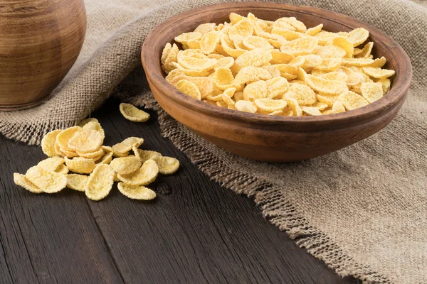 Corn flakes in ceramic bowl on the old wooden table.