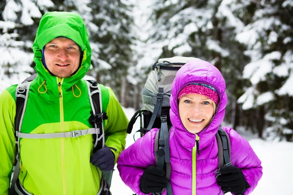 Couple happy hikers trekking in winter woods