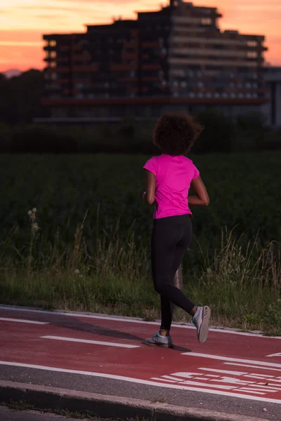 A young African American woman jogging outdoors