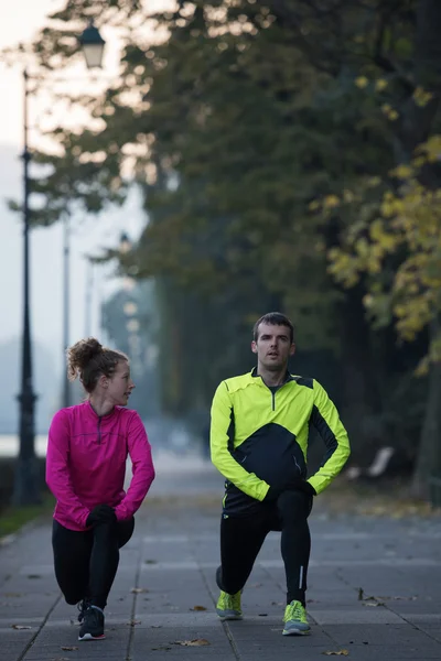 A young couple warming up before jogging