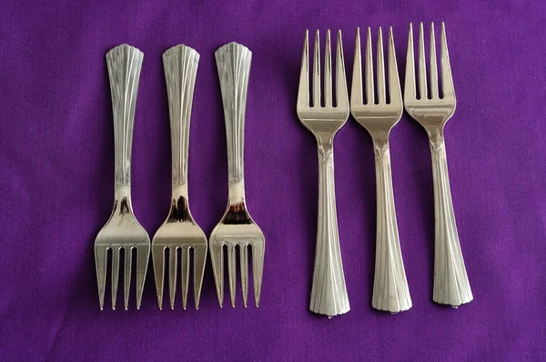 A row of cake forks isolated on a purple background