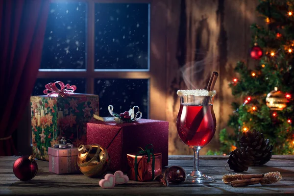 glass with mulled wine with gift boxes on color back