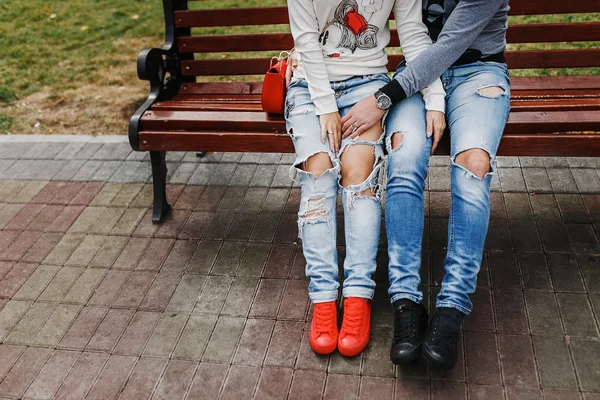 Stylish man and woman in love hugging. Close-up of ripped jeans and sneakers. The concept of a style couple