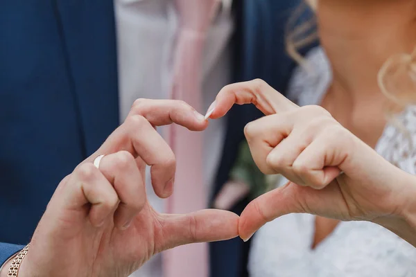 The bride and groom\'s hands make a heart shape