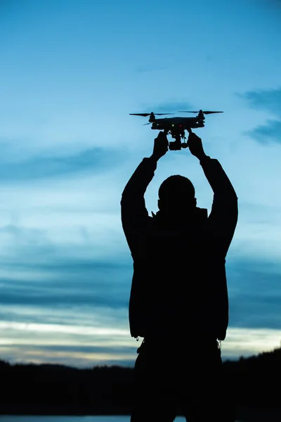 Man holding a drone for aerial photography. Silhouette against the sunset sky