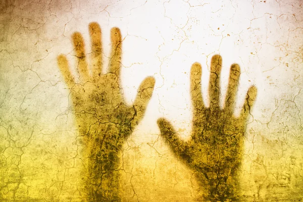 Back lit silhouette of trapped person hands behind matte glass