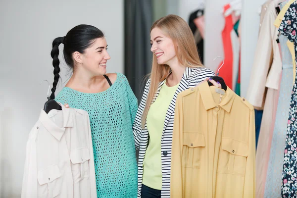 Smiling women holding dresses