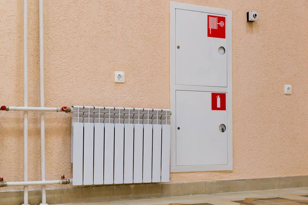 Wall of room with a sink,  fire hydrant and  extinguisher