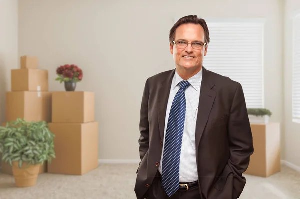 Businessman in Empty Room with Packed Boxes and Plants