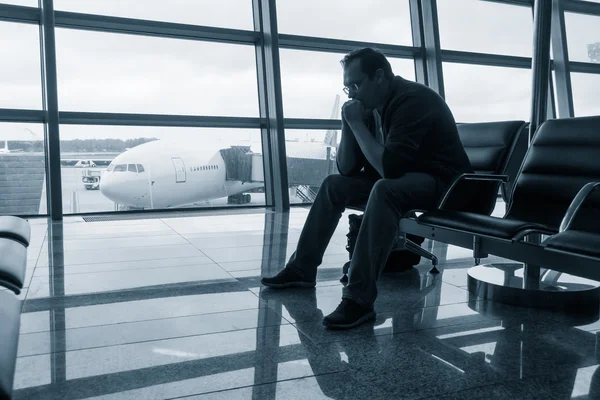 Sad man waiting for delayed flight