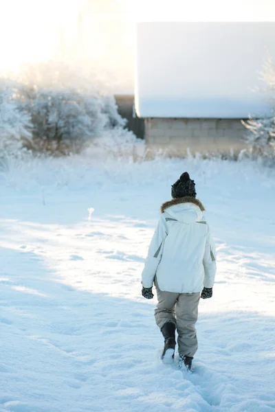 Old elderly woman in warm clothes walking home through heavy snow on a cold winter morning at sunrise