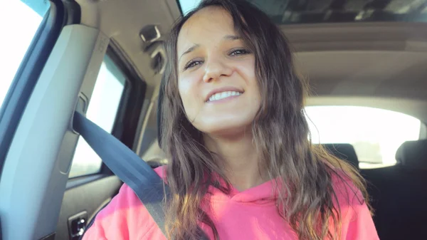 Joyful beautiful young woman smiling in car
