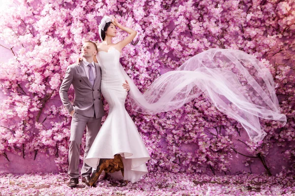 Wedding couple against wall with flowers