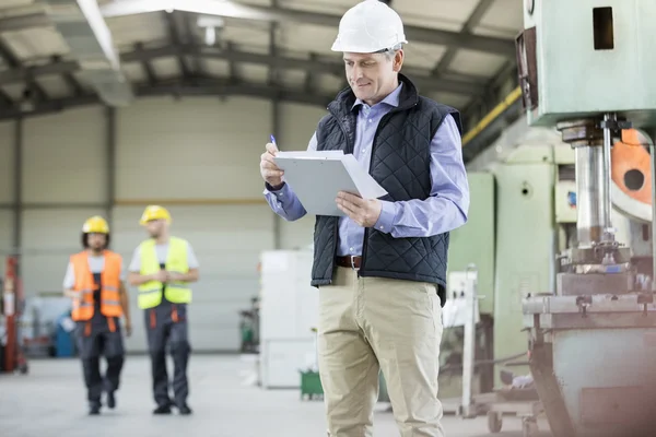 Inspector writing on clipboard  at factory