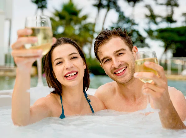 Couple in jacuzzi with wineglasses in hands