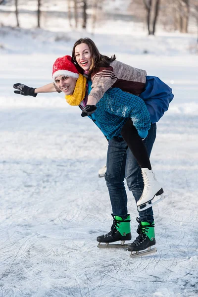 Happy couple having fun ice skating on rink outdoors.