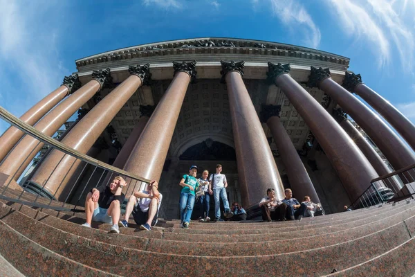 Tourists walk in the shadow of the majestic columns of St. Isaac