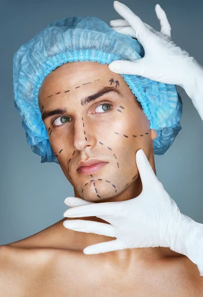 Attractive man patient with guideline marks on his face before plastic surgery operation.