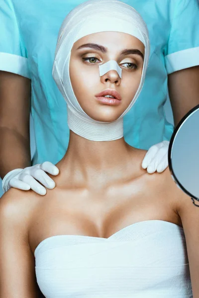 Girl model after plastic surgery wrapped in medical bandages