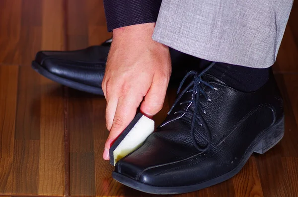 Closeup mans formal black shoes, using sponge to polish leather, men getting dressed concept