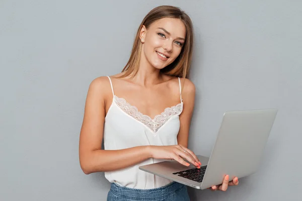 Smiling cute girl using laptop and looking at camera