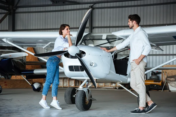 Happy young couple standing near small plane