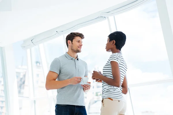 Two young business people standing and talking in office