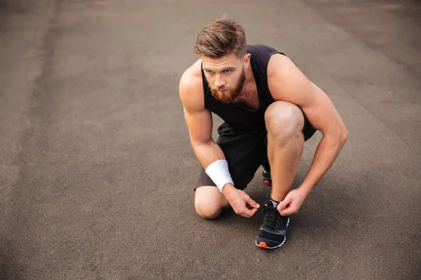 Portrait of man athlete ties his shoelaces