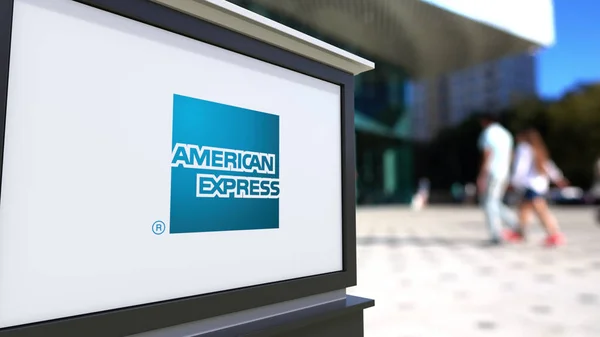 Street signage board with American Express logo. Blurred office center and walking people background. Editorial 3D rendering