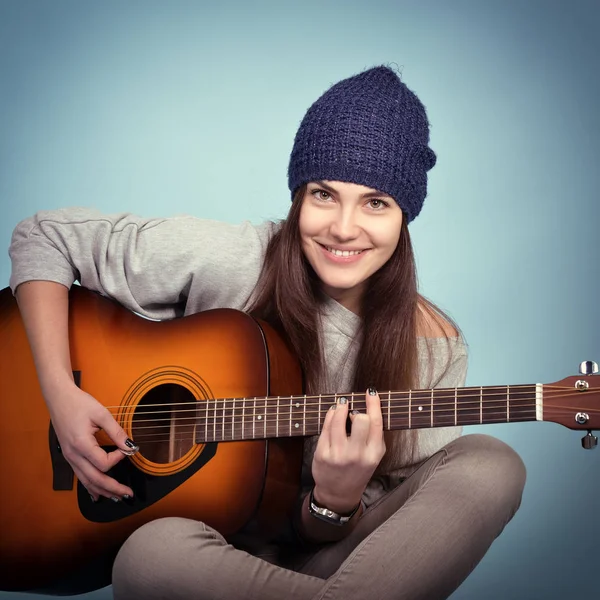 Young woman playing on guitar