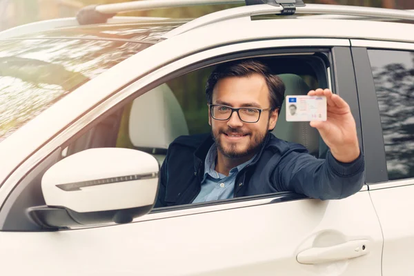 Young happy man showing his new driver license