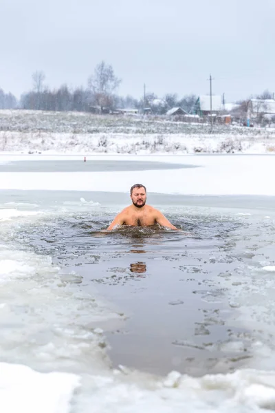 Winter swimming. Man in ice-hole