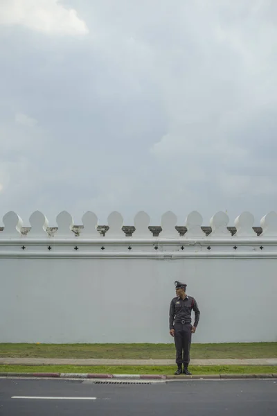 A police standing in front of The Grand Palace road.