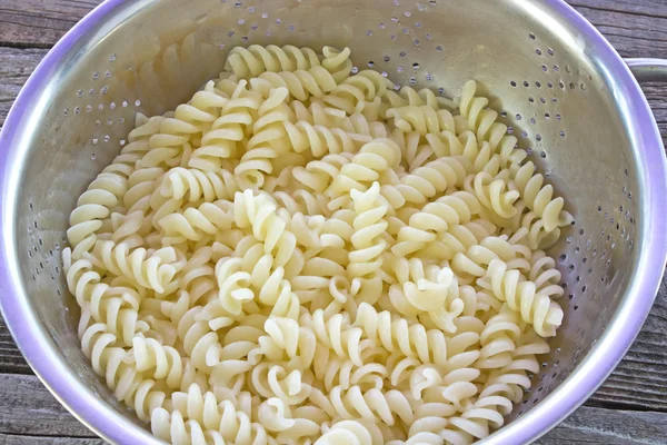 Fresh cooked fusilli pasta in strainer on table